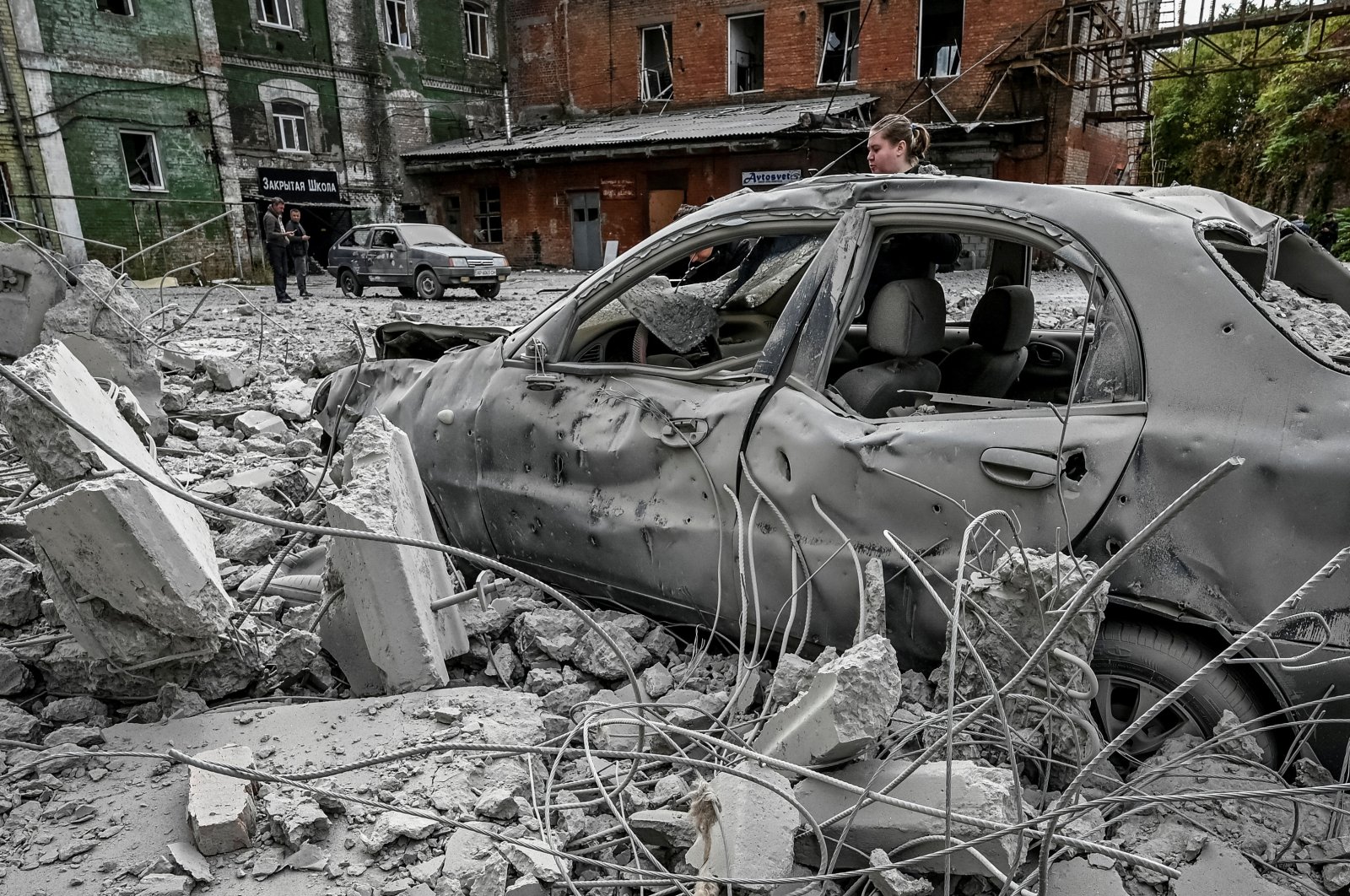 A woman stands near her destroyed car near an old mill, built around 1885, also destroyed during a Russian missile attack, Zaporizhzhia, Ukraine Oct.14, 2022. (REUTERS Photo)