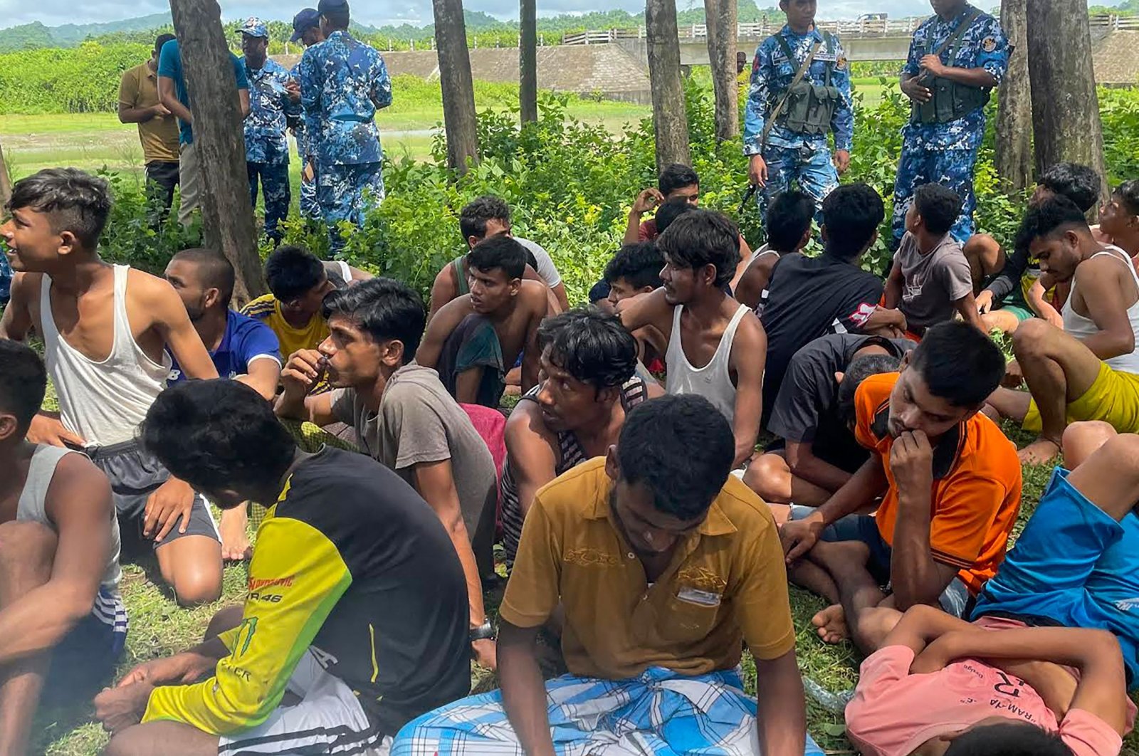 Members of Bangladesh security personnel stand guard beside Rohingya refugees rescued from the sea after a Malaysia-bound boat sank off the Bangladesh coast, Teknaf, Bangladesh, Oct. 4, 2022. (AFP Photo)