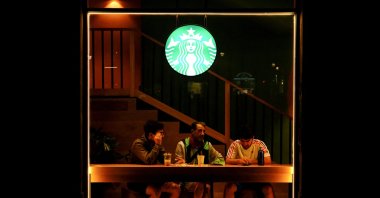 A Starbucks logo is seen as men sit at a Starbucks coffee shop in Barcelona, Spain, Oct. 15, 2022. (Reuters Photo)