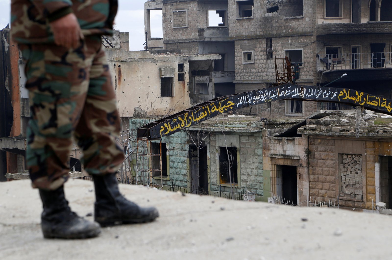 A Syrian regime soldier stands on a roof near a street sign that was written by opposition forces in the streets of Maarat al-Numan, Syria, Jan. 30, 2020. (Reuters Photo)