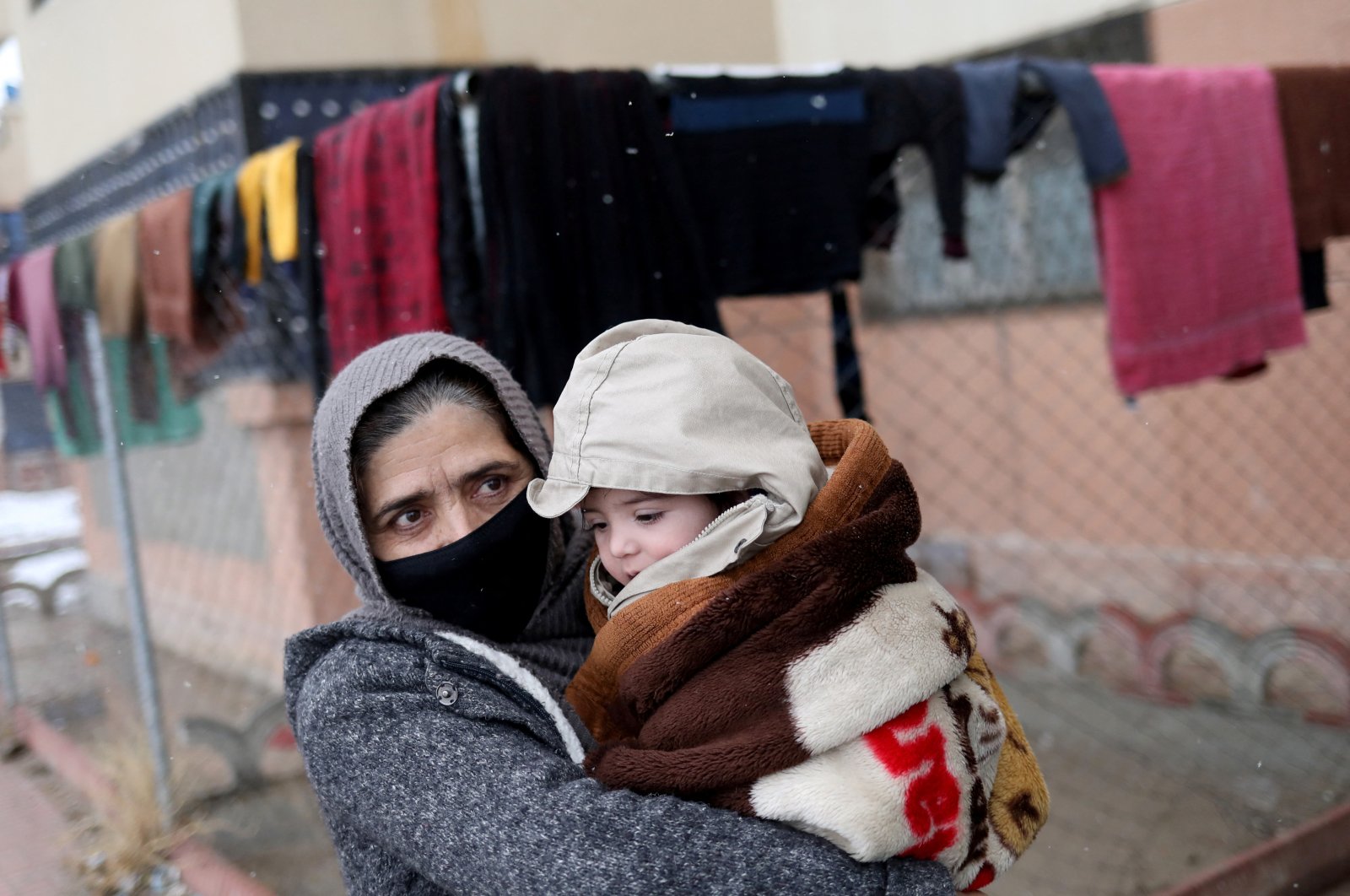 Baby Sohail Ahmadi is carried by his grandmother as they leave then house of Hamid Safi, a 29-year-old taxi driver who had found Sohail at the airport, in Kabul, Afghanistan, Jan. 8, 2022. (Reuters File Photo)