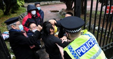 A Hong Kong pro-democracy protester (C) and Chinese consulate staff scuffle as a British police officer attempts to intervene during a demonstration outside the consulate, Manchester, England, Oct. 16, 2022. (AFP Photo)