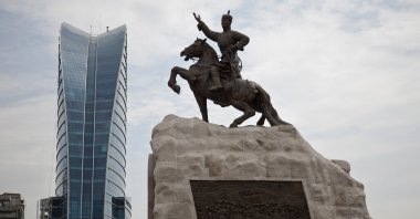 Mongolian children play near a statue of Damdin Sukhbaatar, leader of Mongolia’s 1921 revolution at Sukhbaatar Square in Ulan Bator, Mongolia, July 2, 2012. (AP Photo)