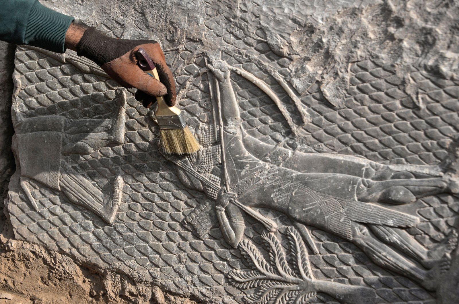 An Iraqi worker excavates a rock-carving relief recently found at the Mashki Gate, one of the monumental gates to the ancient Assyrian city of Nineveh, on the outskirts of Mosul, Iraq, Oct. 19, 2022. (AFP Photo)