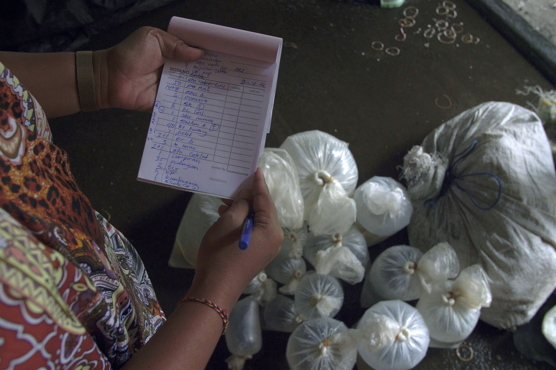 Seorang pekerja memeriksa daftar sortir dan pesanan di area perantara di Les, Bali, Indonesia, 10 April 2021. (AP Photo)