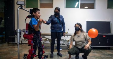 David Zabala is assisted by a physical therapist and his mother, during a rehabilitation session, at the Association for People with Cerebral Palsy in Mexico City, Mexico, Oct. 18, 2022. (AFP Photo)