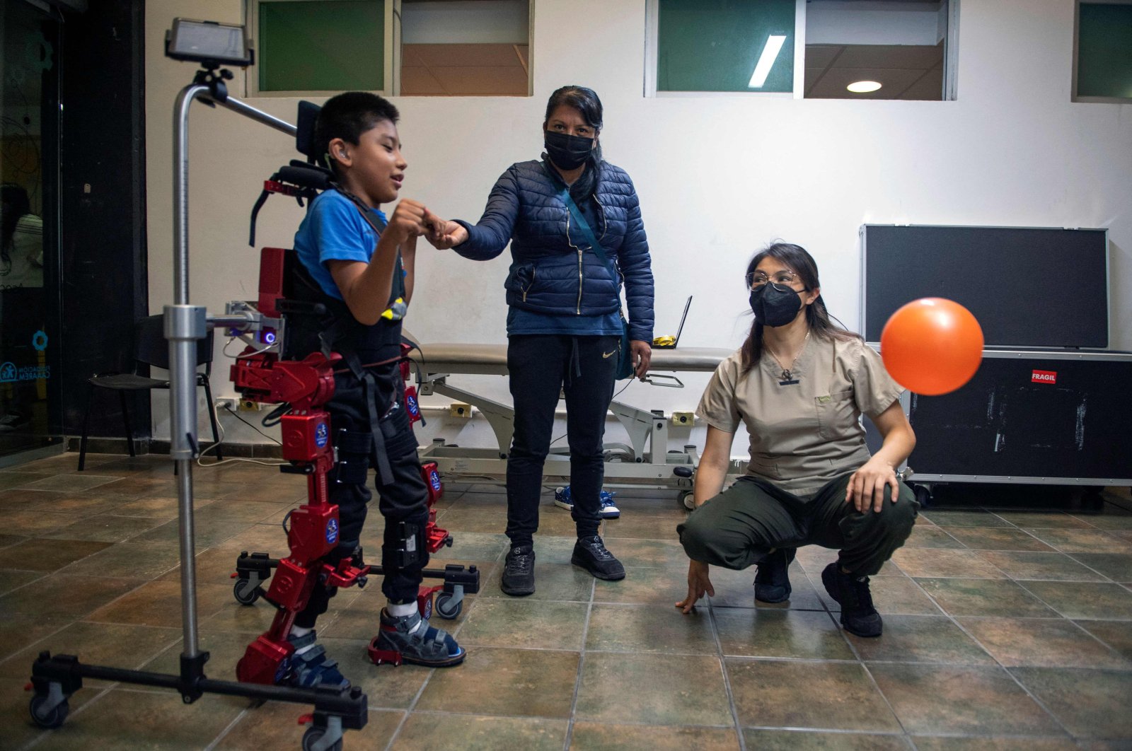 David Zabala is assisted by a physical therapist and his mother, during a rehabilitation session, at the Association for People with Cerebral Palsy in Mexico City, Mexico, Oct. 18, 2022. (AFP Photo)
