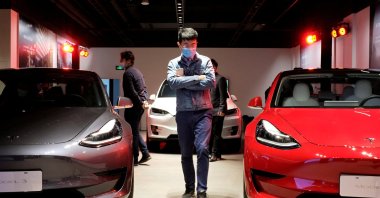 A man wearing a face mask following the coronavirus disease (COVID-19) outbreak walks by Tesla Model 3 sedans and Tesla Model X sport utility vehicles at a new Tesla showroom in Shanghai, China, May 8, 2020. (Reuters Photo)