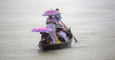 People cross the Buriganga river as they hold umbrellas during heavy rain and rough condition caused by cyclone Sitrang, Dhaka, Bangladesh, Oct. 24, 2022. (EPA Photo)