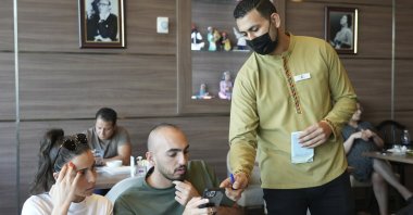 Ali el-Sayyed Mohammed takes an order from customers at Hadoota Masreya Restaurant in Dubai, United Arab Emirates, Sept. 5, 2022. (AP Photo)