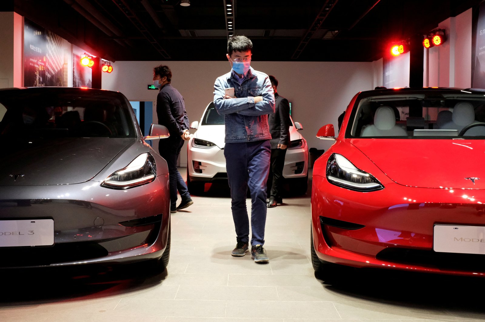 A man wearing a face mask following the coronavirus disease (COVID-19) outbreak walks by Tesla Model 3 sedans and Tesla Model X sport utility vehicles at a new Tesla showroom in Shanghai, China, May 8, 2020. (Reuters Photo)