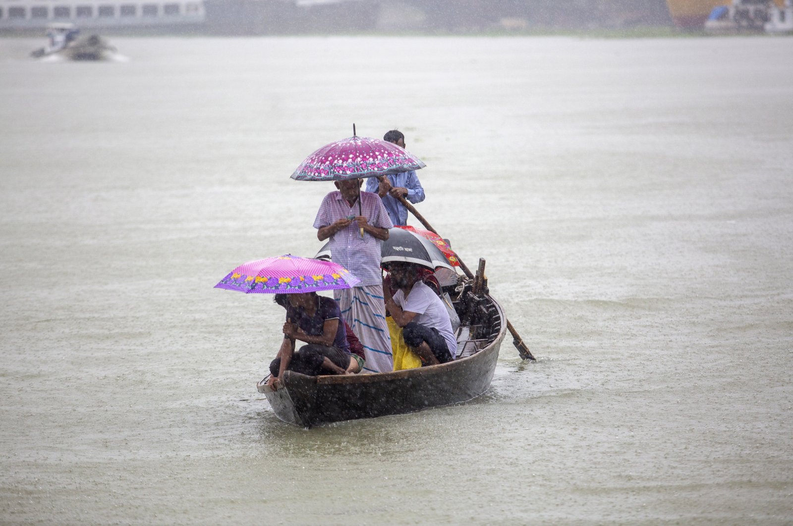 People cross the Buriganga river as they hold umbrellas during heavy rain and rough condition caused by cyclone Sitrang, Dhaka, Bangladesh, Oct. 24, 2022. (EPA Photo)