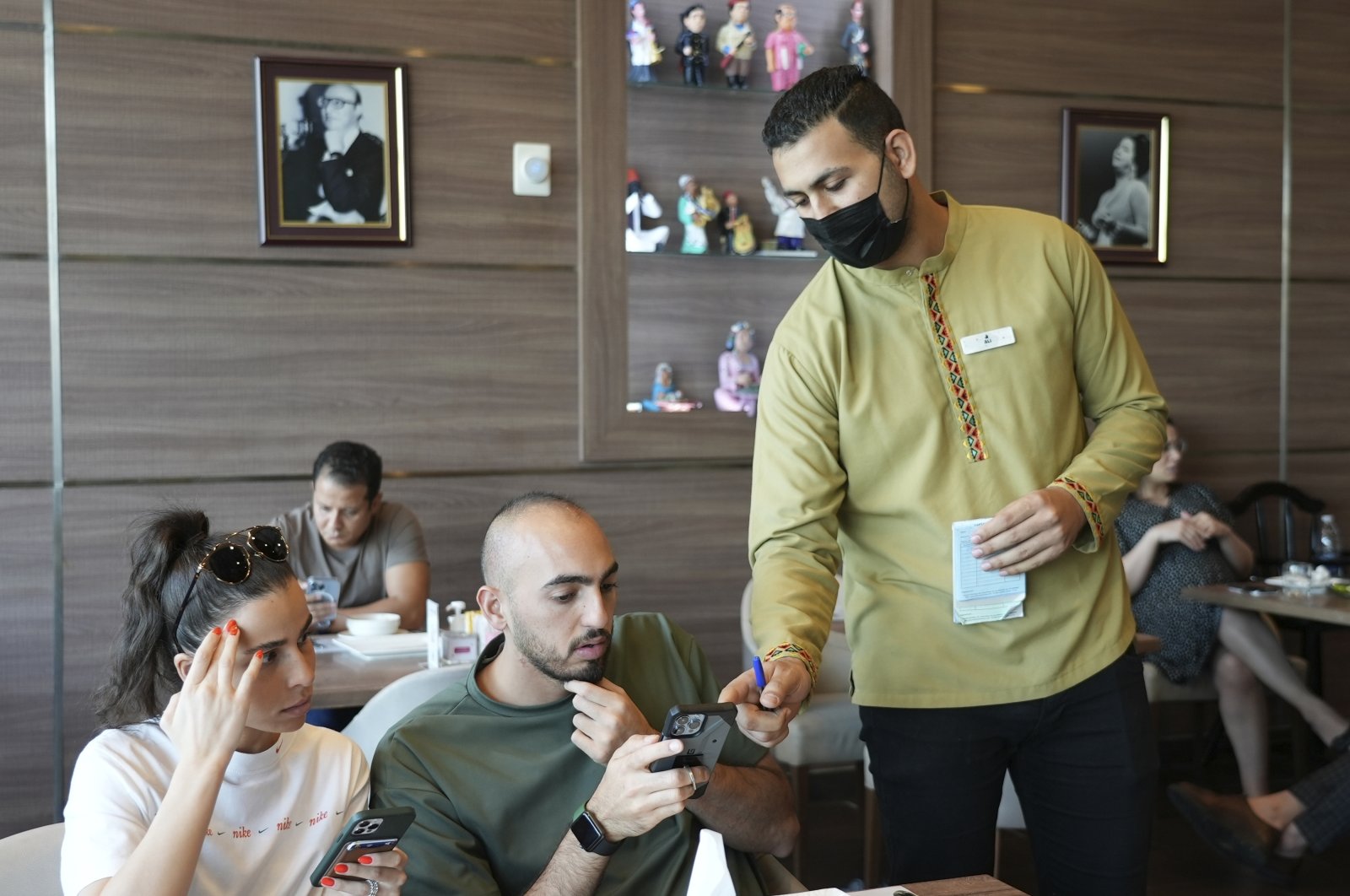 Ali el-Sayyed Mohammed takes an order from customers at Hadoota Masreya Restaurant in Dubai, United Arab Emirates, Sept. 5, 2022. (AP Photo)