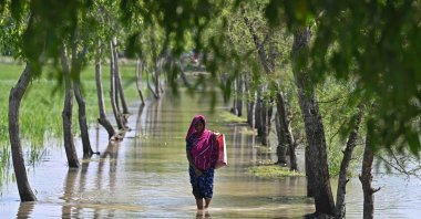 A woman wades through clogged tidal water in the aftermath of Cyclone Sitrang, Patuakhali, southwestern Bangladesh, Oct. 25, 2022. (AFP Photo)