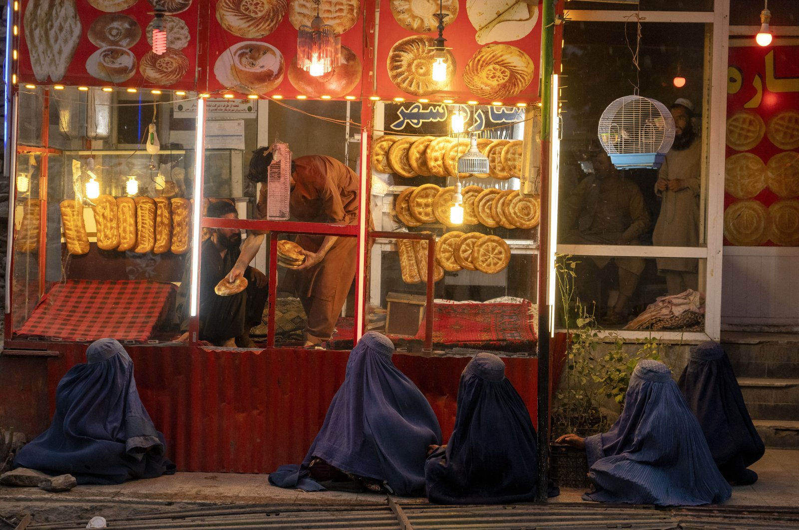 Begging women wait to receive alms in front of a bakery shop in Parwan province north of Kabul, Afghanistan, May 19, 2022. (AP Photo)