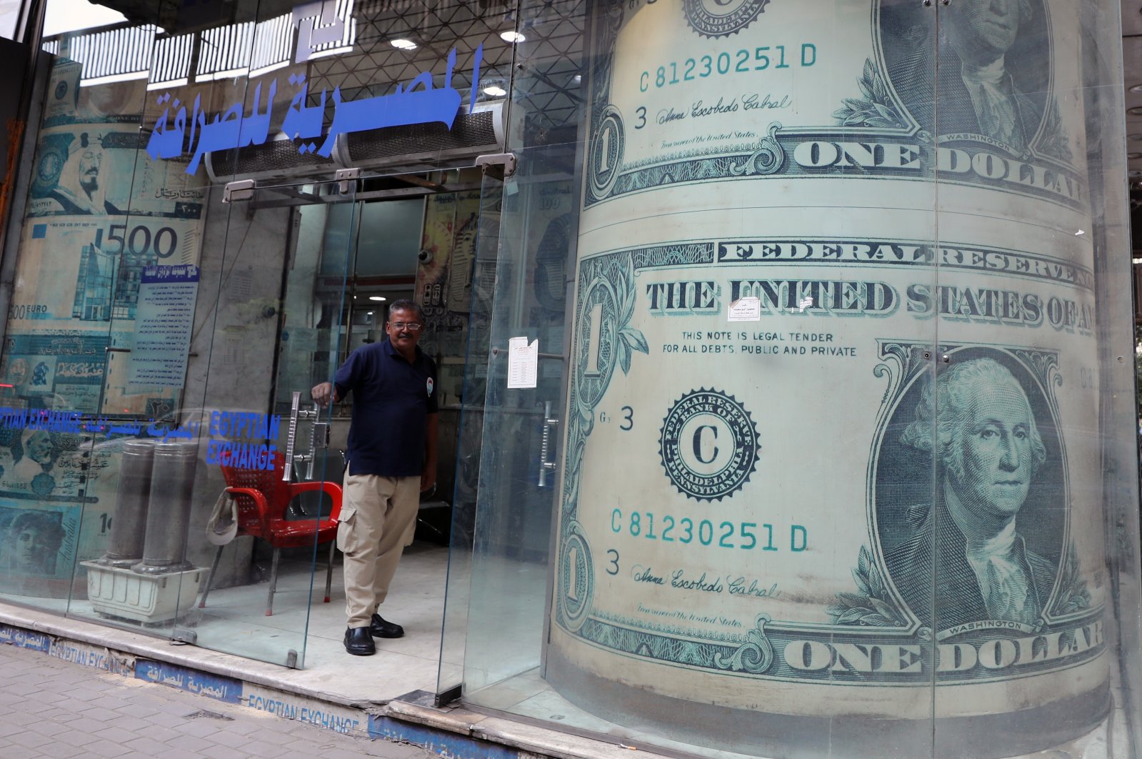 Egyptian guard stands outside a currency exchange office with a large-scale image of the U.S. dollar in Cairo, Egypt, Oct. 27, 2022. (EPA Photo)