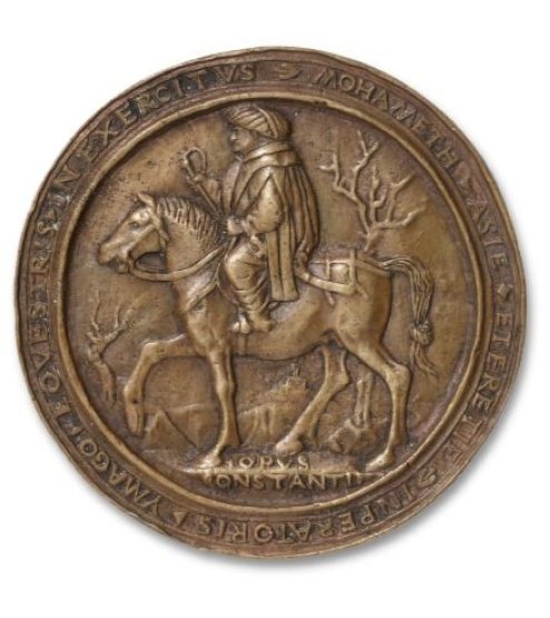 Sisi belakang koin menggambarkan Sultan Mehmed Sang Penakluk di atas kuda dengan tulisan “Muhammad, Kaisar Asia dan Yunani, Potret Berkuda dalam kampanye,