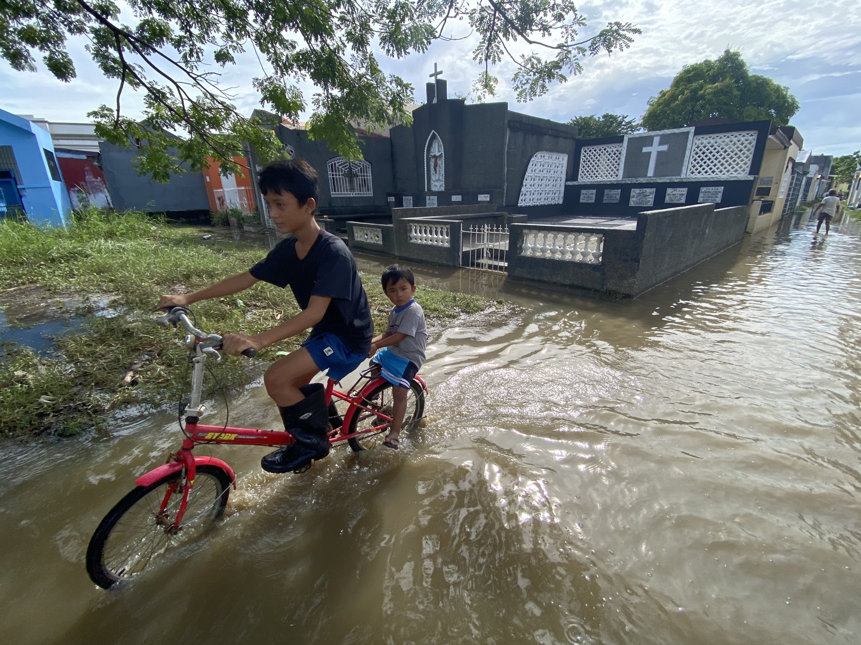 Anak-anak Filipina mengendarai sepeda di pemakaman yang banjir, Cavite, Filipina, 31 Oktober 2022. (EPA Photo)