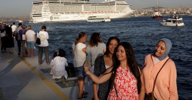 People pose for a selfie at Galataport as a cruise ship sails in the Bosporus in Istanbul, Türkiye, Sept. 17, 2022. (Reuters Photo)