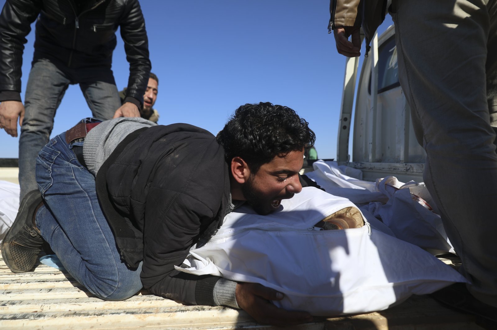 A man mourns over the bodies during the funeral of six family members filed in shelling in the Maaret al-Naasan village in Idlib province, Syria, Feb. 12, 2022. (AP Photo)