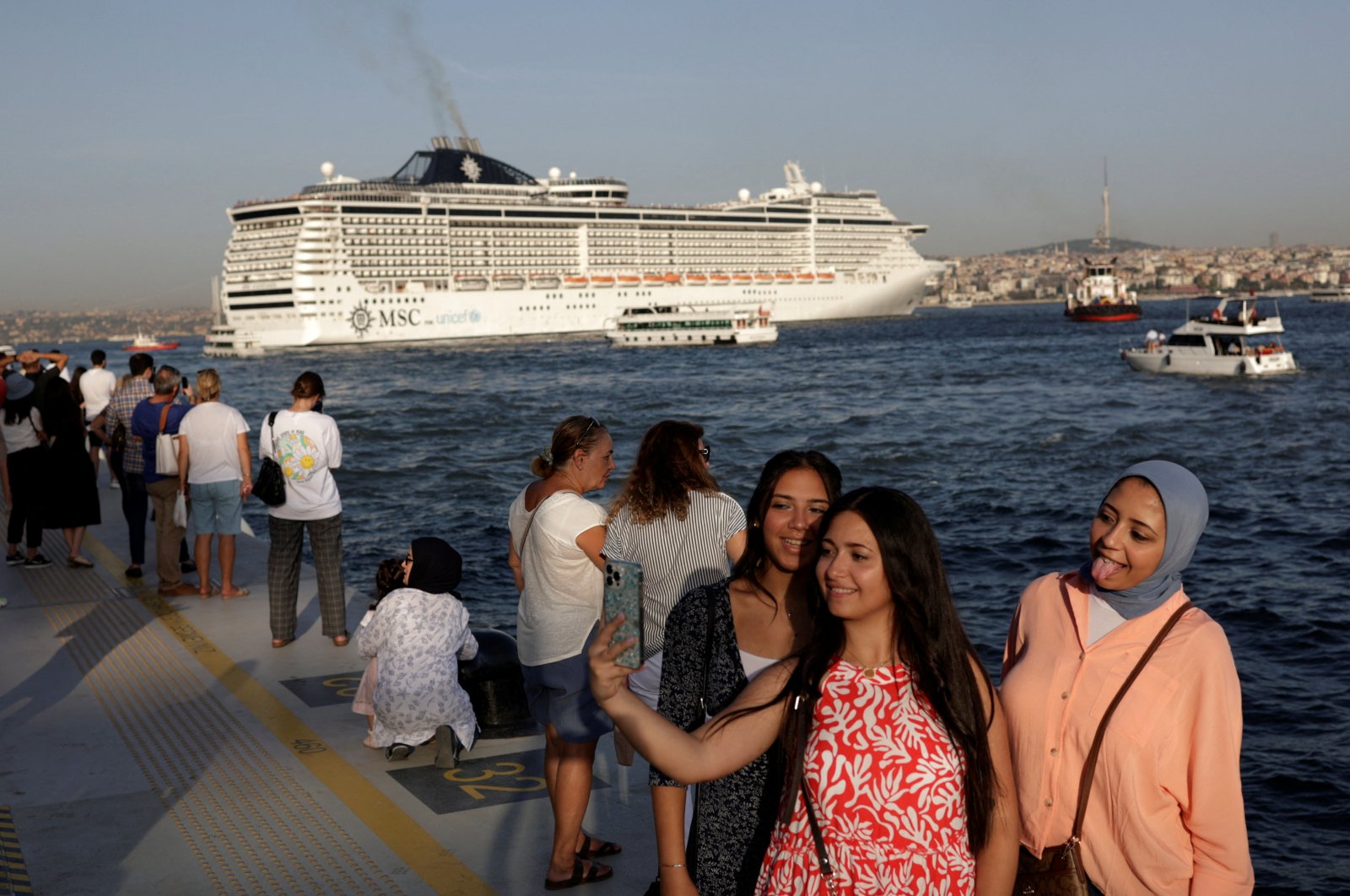 People pose for a selfie at Galataport as a cruise ship sails in the Bosporus in Istanbul, Türkiye, Sept. 17, 2022. (Reuters Photo)