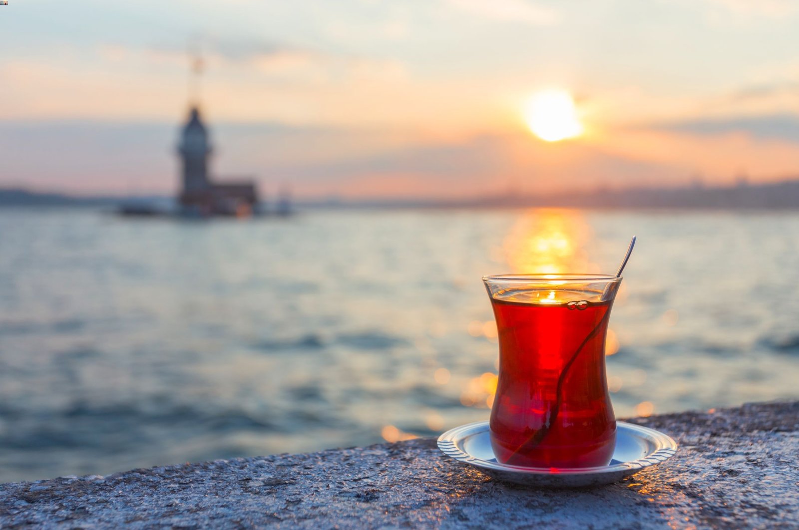 A cup of Turkish tea against the Maiden Tower, in Istanbul, Türkiye. (Shutterstock Photo)