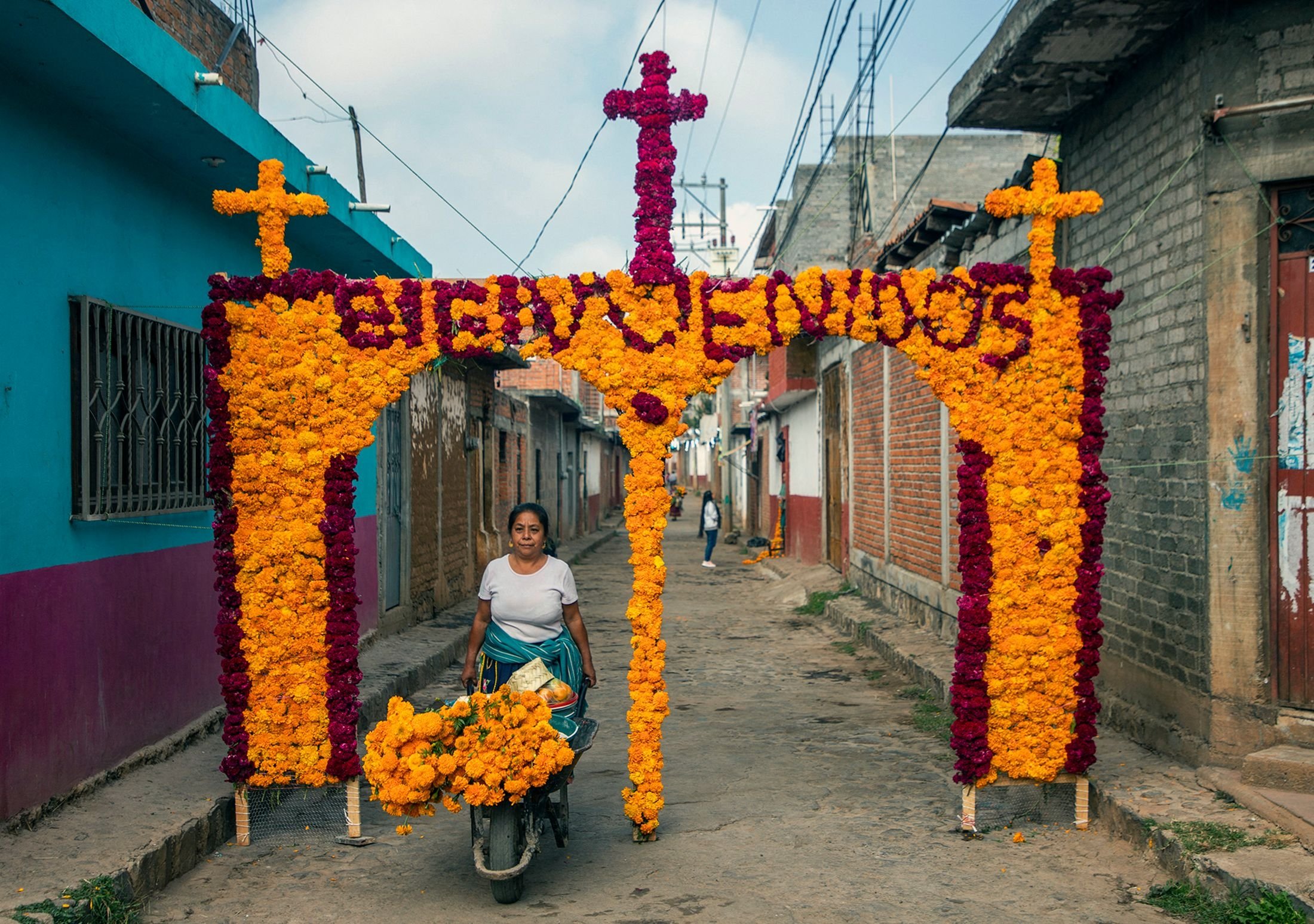 Kerabat Maria Salud Ramirez Caballero, yang dikenal sebagai Mama Coco, menghiasi sebuah lengkungan dengan bunga di jalan tempat dia tinggal untuk menerima kunjungan wisatawan di Santa Fe de la Laguna, negara bagian Michoacan, Meksiko, 31 Oktober 2022. (AFP Foto)