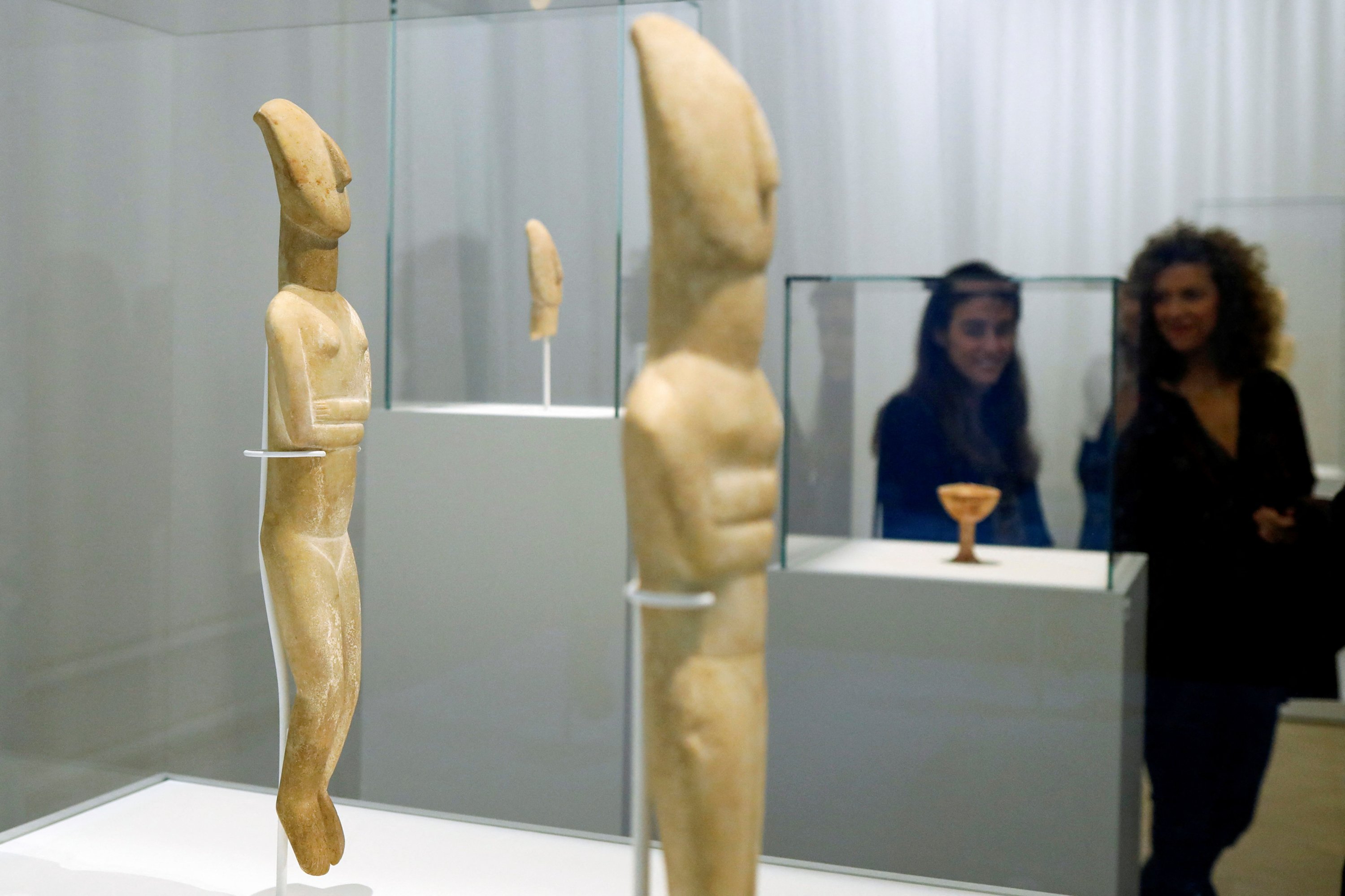 Orang-orang melihat patung-patung wanita Cycladic marmer, selama pembukaan pameran ''Homecoming.  Harta karun Cycladic dalam perjalanan pulang mereka'' di Museum of Cycladic Art, Athena, Yunani, 2 November 2022. (Foto Reuters)