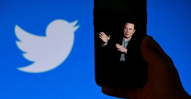A phone screen displays a photo of Elon Musk with the Twitter logo shown in the background, in Washington, D.C., U.S., Oct. 4, 2022. (AFP Photo)