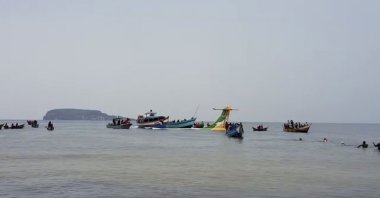 Rescuers in boats are seen around the tail fin of a crashed Precision Air passenger aircraft on the shores of Lake Victoria in Bukoba, Tanzania, Nov. 6, 2022. (AP Photo)