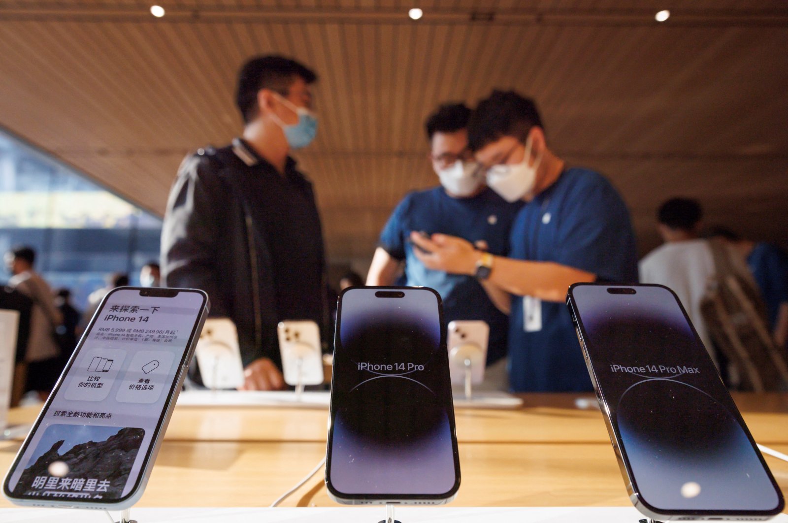 A customer talks to sales assistants in an Apple store as Apple Inc&#039;s new iPhone 14 models go on sale in Beijing, China, Sept. 16, 2022. (Reuters Photo)