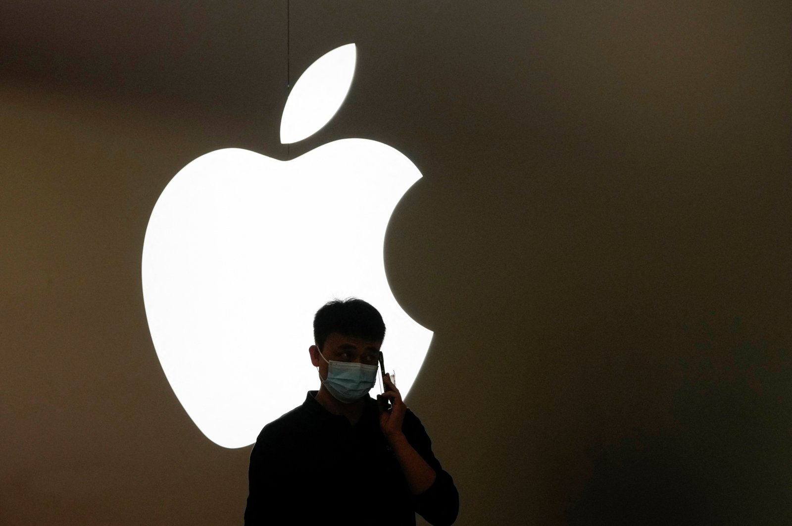A man talks on a phone in front of an Apple logo outside the Apple store following the COVID-19 outbreak in Shanghai, China, Nov. 7, 2022. (Reuters Photo)