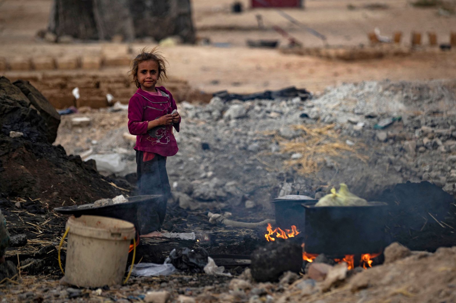 A Syrian girl stands near cooking pots placed on fire at the Sahlah al-Banat camp for displaced people in the countryside of Raqqa, northern Syria, Nov. 7, 2022. (AFP Photo)