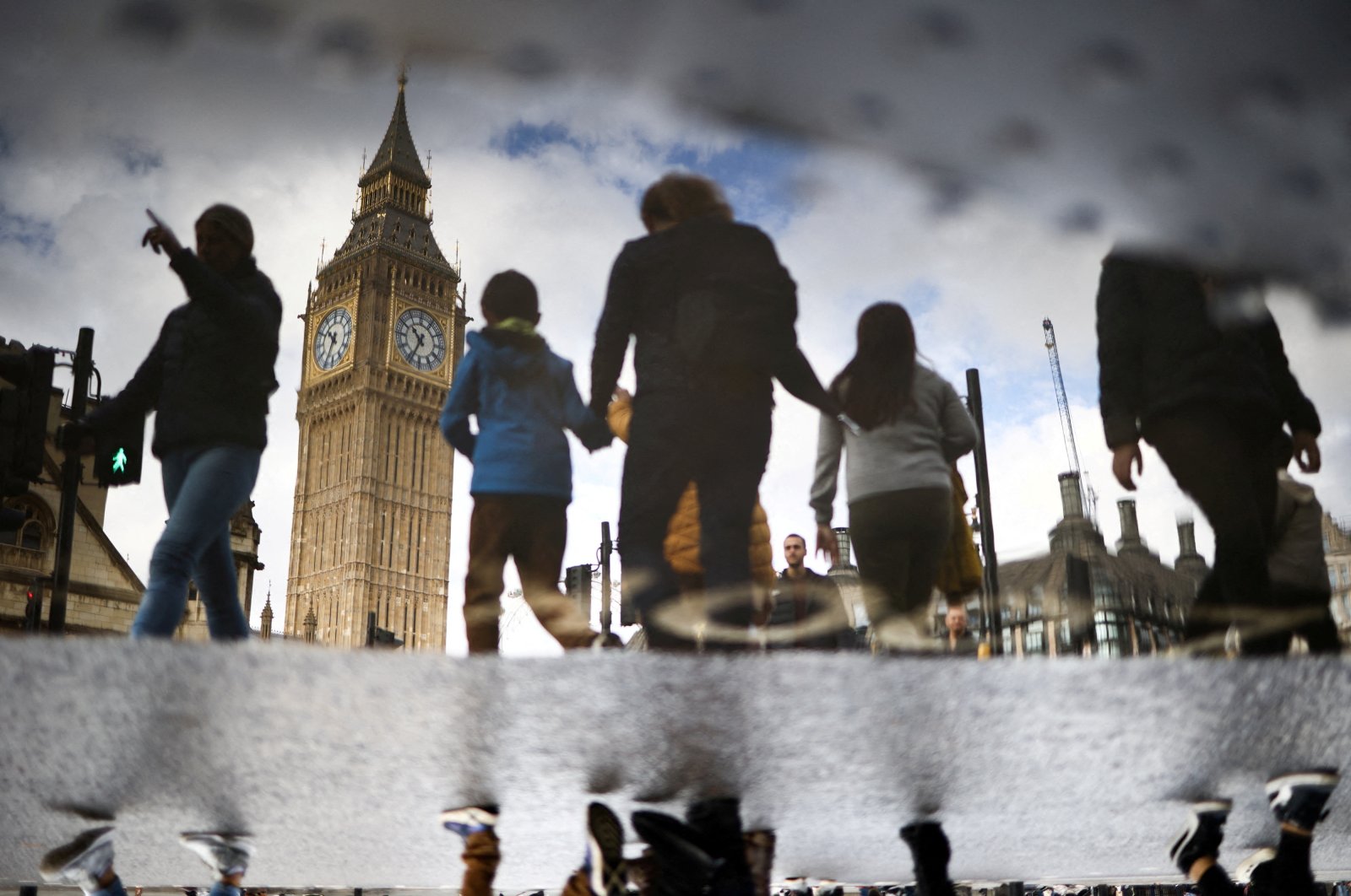 The Elizabeth Tower, more commonly known as Big Ben, is seen reflected in a puddle as people walk outside the Houses of Parliament in London, U.K., Oct. 23, 2022. (Reuters Photo)