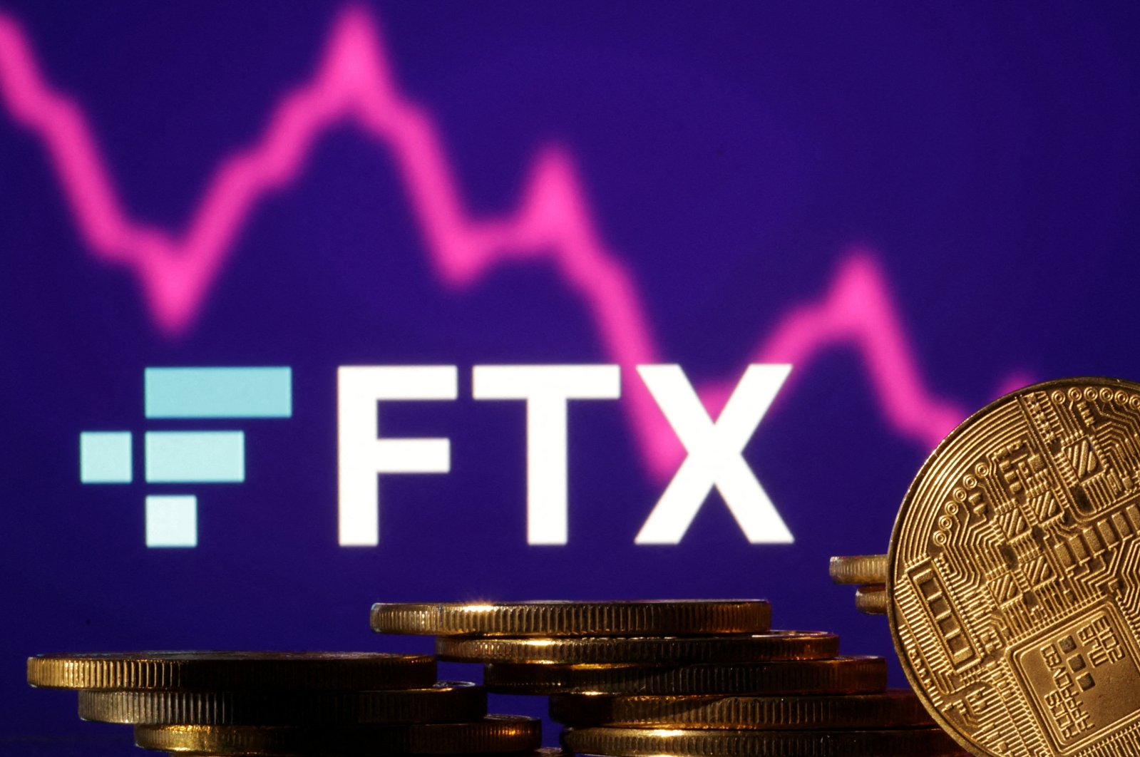 Representations of cryptocurrencies are seen in front of a displayed FTX logo and decreasing stock graph in this illustration taken on Nov. 10, 2022. (Reuters File Photo)