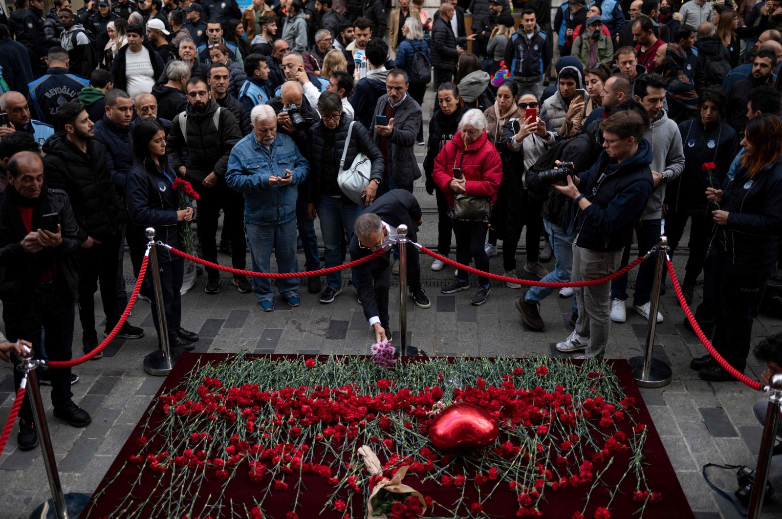 A mourner lays flowers as people grieve the victims of November 13 terror attack at Istiklal Street, in Istanbul, Türkiye, Nov. 14, 2022. (AFP Photo) 