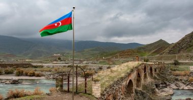 An Azerbaijani national flag flies next to the medieval Khudaferin bridge in Jebrayil district at the country&#039;s border with Iran, Azerbaijan, Dec. 9, 2020. (AFP Photo)