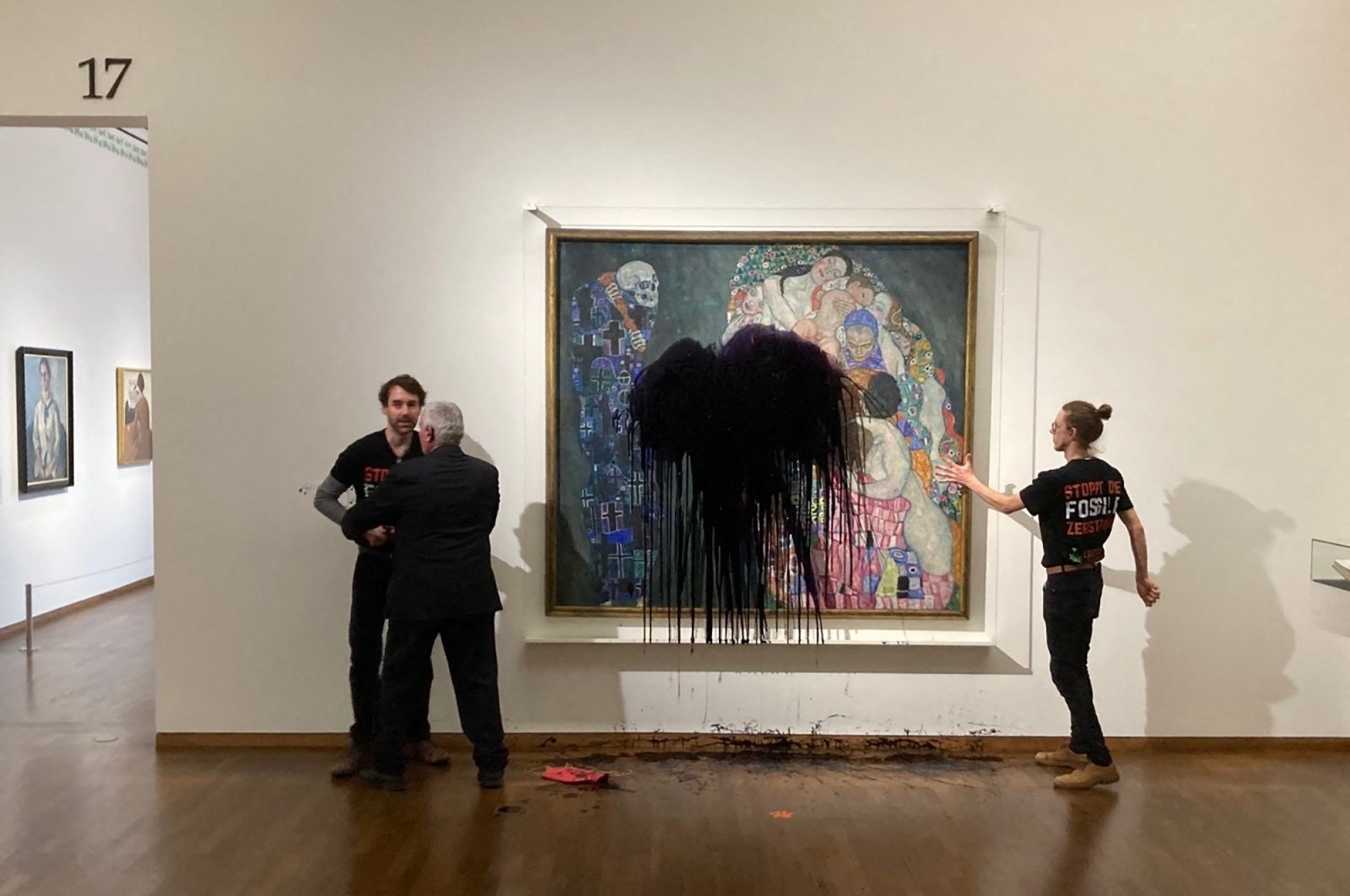 The picture shows a climate activist of the &quot;Last Generation&quot; group being overpowered whereas another one has glued himself to the painting &quot;Death and Life&quot; by Austrian artist Gustav Klimt after pouring black liquid over the artwork at the Leopold Museum in Vienna, Austria, Nov. 15, 2022. (AFP Photo)