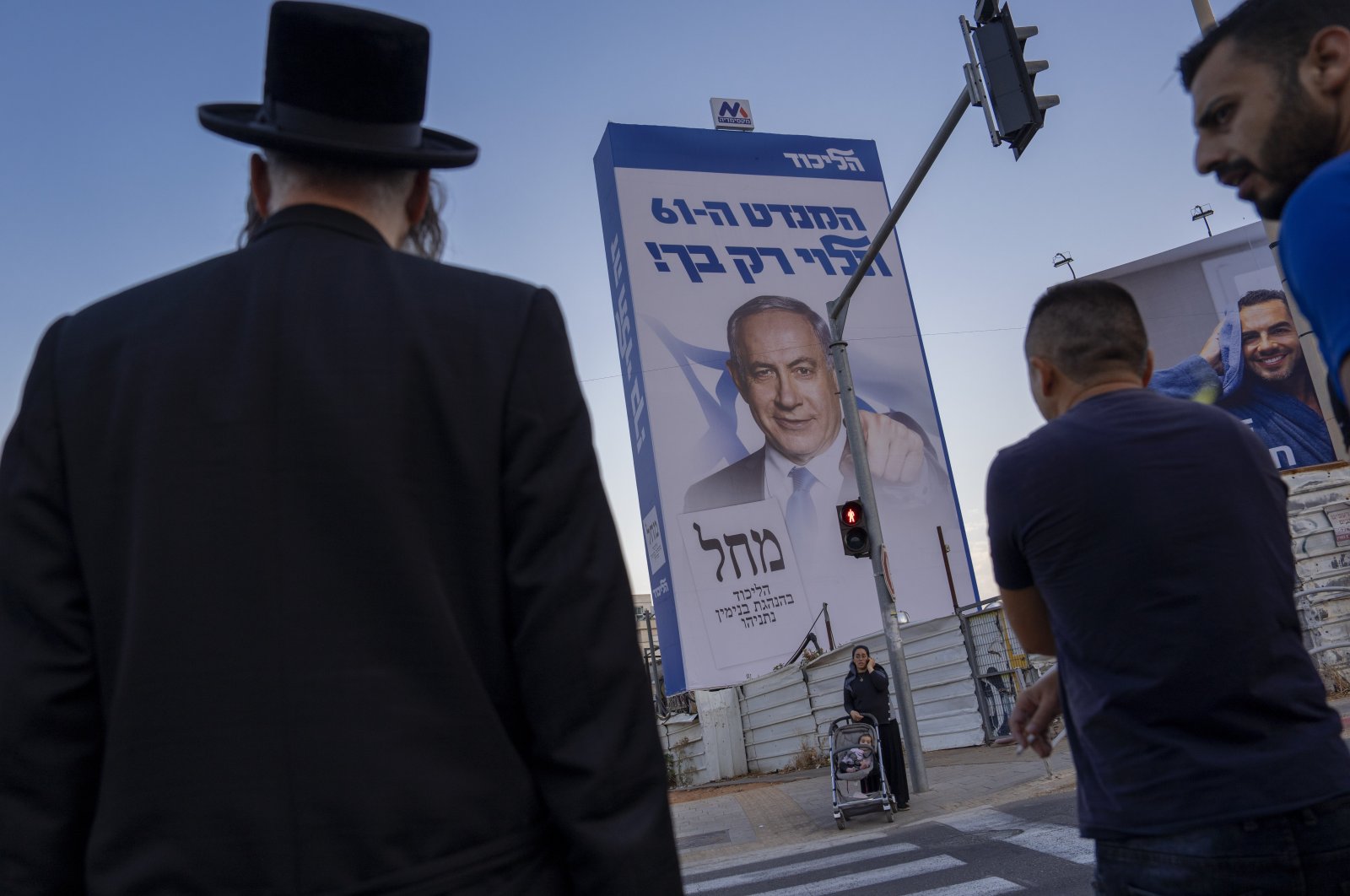 People walk past an election campaign billboard showing Benjamin Netanyahu, Bnei Brak, Israel, Oct. 25, 2022. (AP Photo)