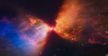 The Protostar within the dark cloud L1527 with ejections from the star above and below appearing orange and blue in infrared view. (AFP Photo)