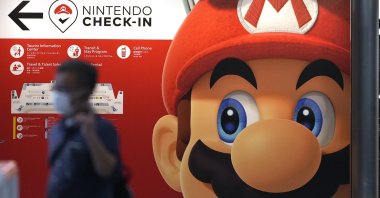 A traveler walks past an advertisement featuring a Nintendo character at Narita airport in Narita near Tokyo, Japan, June 10, 2022. (AP Photo)