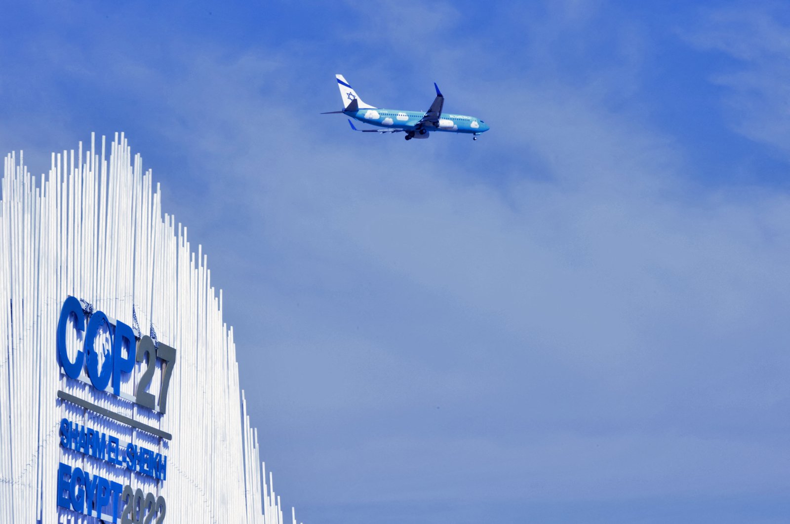 An Israeli El Al passenger plane flies over the Sharm el-Sheikh International Convention Centre, during the COP27 climate conference in Egypt's Red Sea resort city of the same name, on November 17, 2022. (Photo by AHMAD GHARABLI / AFP)