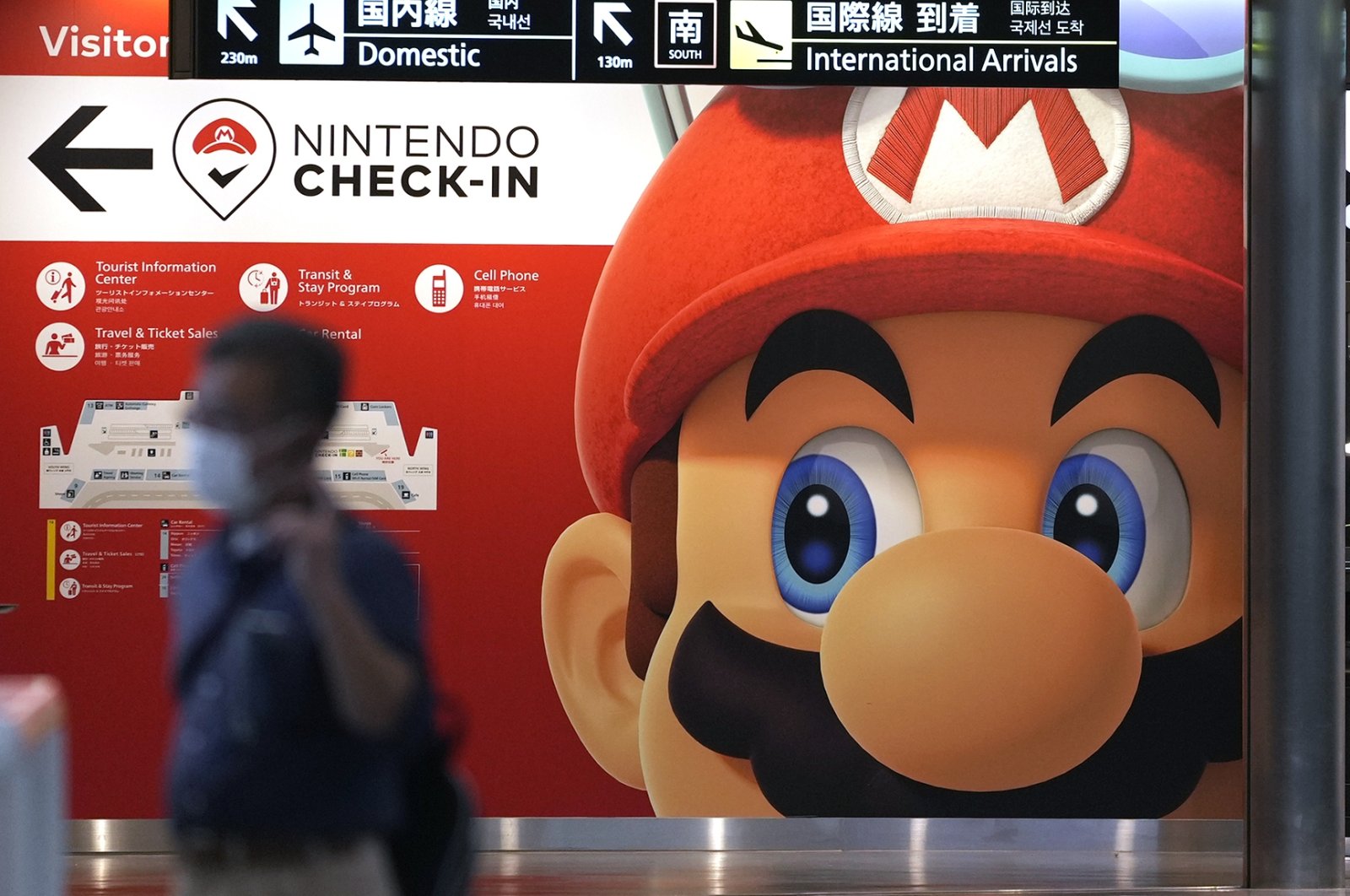 A traveler walks past an advertisement featuring a Nintendo character at Narita airport in Narita near Tokyo, Japan, June 10, 2022. (AP Photo)