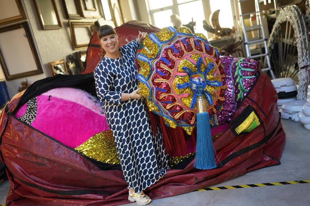 Portuguese artist Joana Vasconcelos poses for a picture while pulling one of her works out of a huge bag at her studio in Lisbon, Portugal, Nov. 11, 2022. (AP Photo)