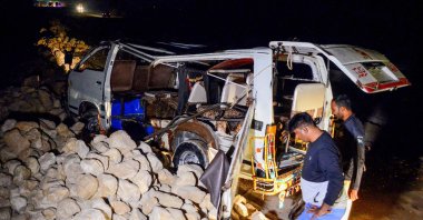 A policeman stands beside a damaged passenger minibus after an overnight accident, Sindh, Pakistan, Nov. 18, 2022. (AFP Photo)