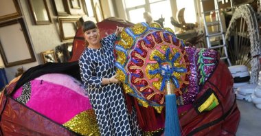 Portuguese artist Joana Vasconcelos poses for a picture while pulling one of her works out of a huge bag at her studio in Lisbon, Portugal, Nov. 11, 2022. (AP Photo)