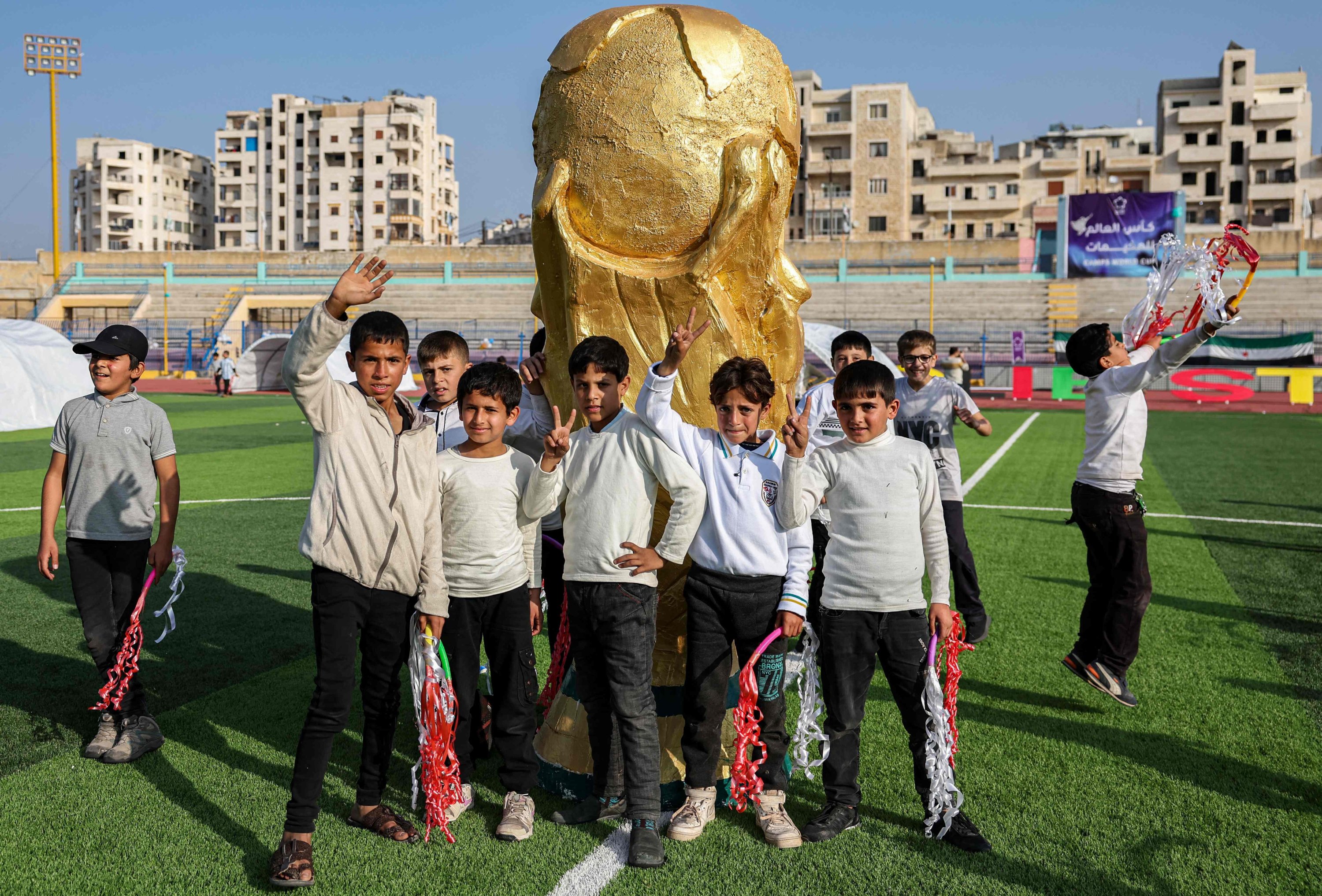 Para pemuda berpose dengan maket trofi Piala Dunia FIFA di lapangan saat upacara pembukaan Piala Dunia 