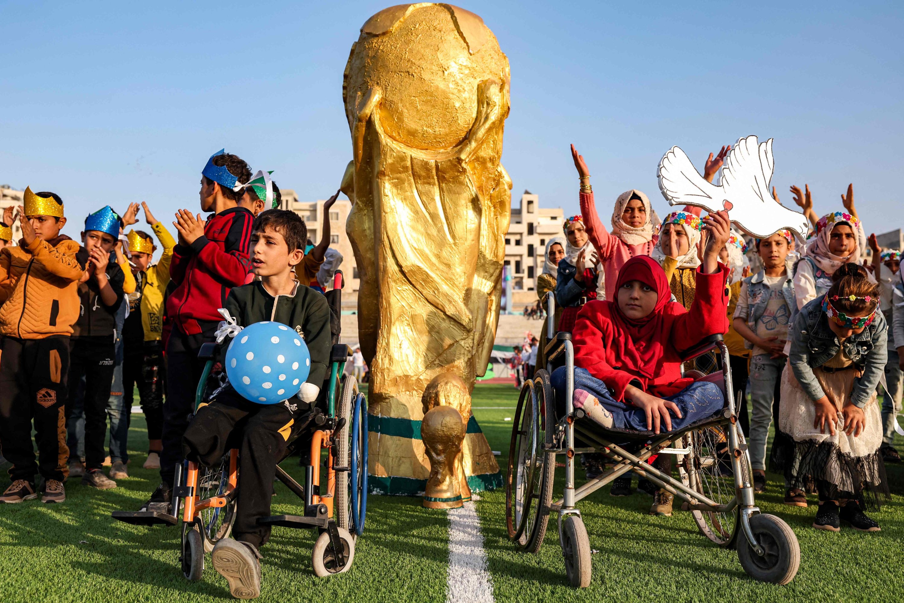 Anak-anak, termasuk mereka yang menggunakan kursi roda, berpose dengan maket trofi Piala Dunia FIFA di lapangan saat upacara pembukaan Piala Dunia 