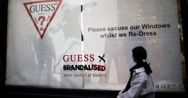 A person walks past the window display of a Guess store that includes the artwork "Flower Thrower" by street artist Banksy, on Regent Street in London, U.K., Nov. 18, 2022. (Reuters Photo)