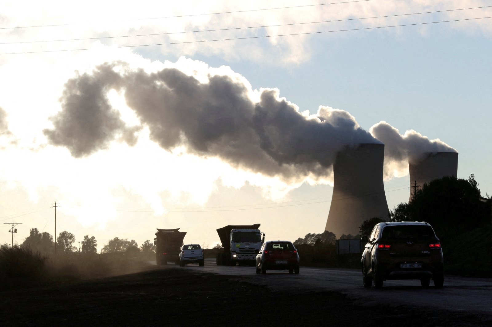 Trucks and cars are seen driving past while smoke rises from the coal-based power station owned by state power utility Eskom, in Emalahleni, Mpumalanga province, South Africa, June 3, 2021. (Reuters Photo)